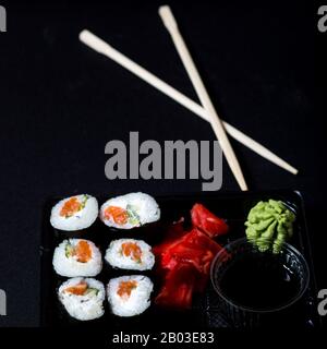 Set of rolls with salmon on black bacground. Sushi in plastick box to go. Stock Photo