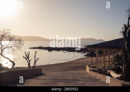 Entrance to Arinella beach in Lumio in the Balagne region of Corsica as the afternoon sun goes down behind the citadel of Calvi in the distance Stock Photo