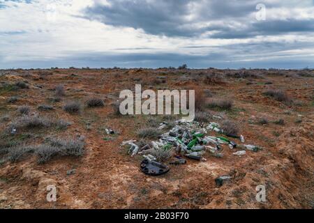 Pile of glass bottles in field, environmental pollution Stock Photo