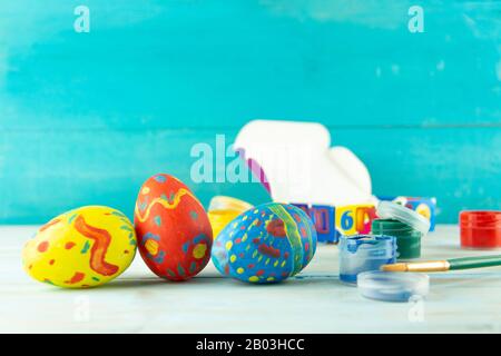 Conceptual image of Easter with Easter eggs on blue wooden background with copyspace and colored red blue green yellow paint with brush Stock Photo