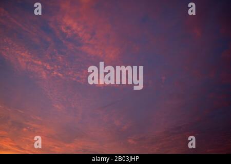 Beautiful colored cloudy skies in the colors blue, magenta, orange, purple, pink and yellow at sunrise in the Netherlands during the winter Stock Photo