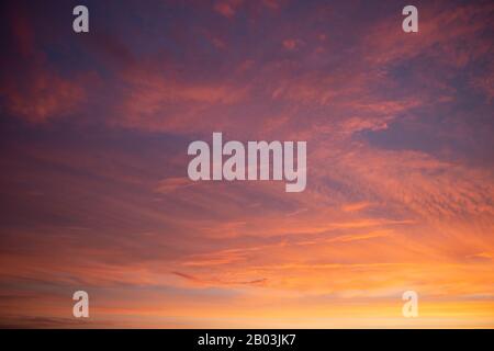 Beautiful colored cloudy skies in the colors blue, magenta, orange, purple, pink and yellow at sunrise in the Netherlands during the winter Stock Photo