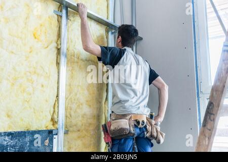 Worker insulating wall of a new building on construction site Stock Photo