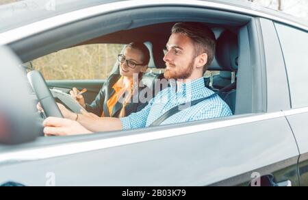 Driving instructor with student in car teaching how to drive Stock Photo