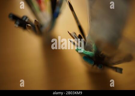 Art supplies on a wooden table. Brushes and pencils in the stand. Selective focus Stock Photo