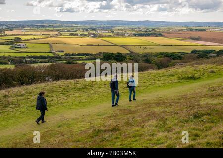 Three ramblers walking along footpaths near St Agnes Head on the Heritage Coast in Cornwall, England. Stock Photo