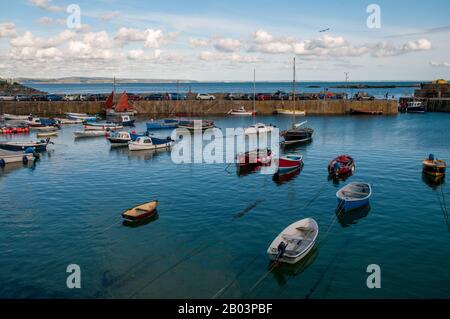 Small recreational and fishing boats are moored inside the breakwater bridge in Mousehole harbour in Cornwall, England. Stock Photo