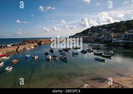 Small recreational and fishing boats are moored inside the breakwater bridge in Mousehole harbour in Cornwall, England. Stock Photo