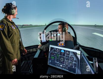 A U.S. Air Force Instructor Pilot, left, with a student pilot in the seat of a T-6 Flight Simulator part of the Predator Reaper drone training program at the 558th Flying Training Squadron, Joint Base San Antonio July 17, 2018 in San Antonio, Texas. Student pilots spend 85 days in the RPA Instrument Qualification course and 30 days in the RPA Fundamentals Course during the second phase of the Air Education and Training Command pilot curriculum. Stock Photo