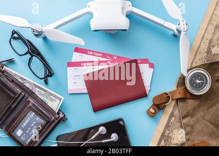 Necessary things for the flight on vacation. Plane tickets, passport, cradit card, phone, drone quadcopter, camera, world map on a blue background. Co Stock Photo