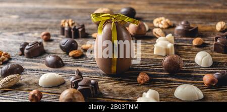 Dark and white chocolate in the shape of eggs and rabbits with nuts on a wooden background. Festive Easter spring greeting card Stock Photo