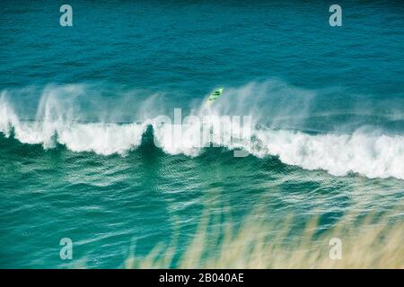 A surf board flies high above a wave as a surfer loses control off Perran Beach, Perranporth, the Cornish Coast, Cornwall England Stock Photo