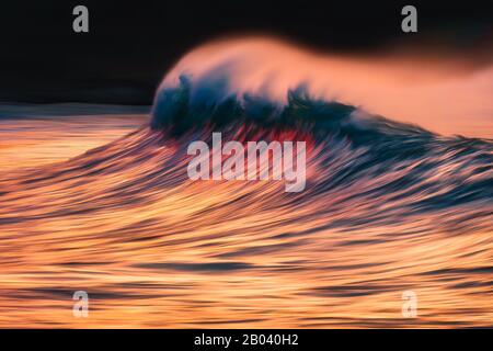 wave with spray breaking at sunset with in camera panning technique Stock Photo