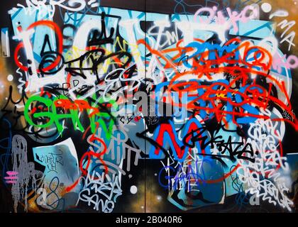 Modern graffiti in a street of the Porta Garibaldi distrect of Milan, Italy, depicting many tags and colored scribbles drawn on an old gate. Stock Photo