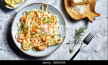 Serving of Italian noodles with fresh scampi garnished with herbs and grated Parmesan cheese viewed from overhead in a flat lay still life Stock Photo