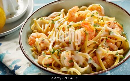 Bowl of fresh scampi with Italian noodles sprinkled with fresh green herbs and melted parmesan cheese in close up for a gourmet Italian or Mediterrane Stock Photo