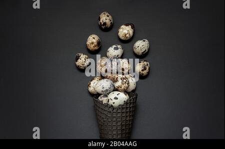 Dark waffle cone with easter eggs on a black background. Space for text. View from above. Flat lay. Stock Photo