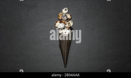 Dark waffle cone with easter eggs on a black background. Space for text. View from above. Flat lay. Stock Photo
