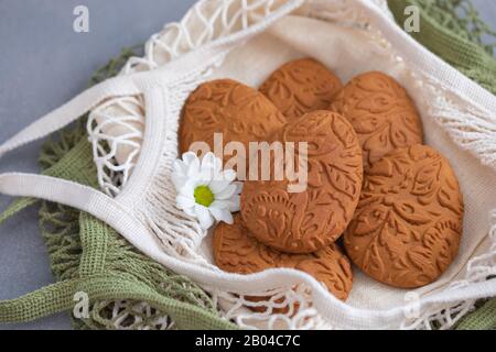 Easter egg shaped ginger cookies on the kitchen towel in the mesh net bag background Stock Photo