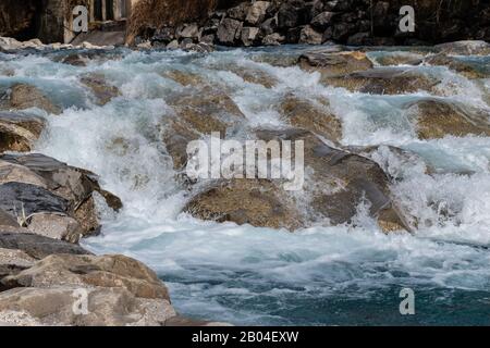 Waves of a mountain river splashing in the strong stream against the stones and boulders of the cascade Stock Photo