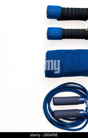 Gym equipment on white background with copy space. Blue dumbbells, skipping rope and towel. Stock Photo