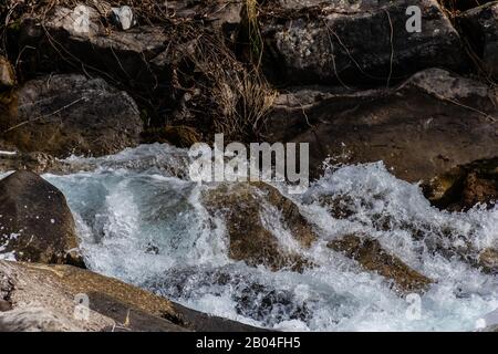 Waves of a mountain river splashing in the strong stream against the stones and boulders of the cascade Stock Photo