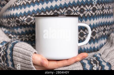 Enamel Mug with black edge line Mock-up. Girl holds white old-tin campfire cup in her hands Stock Photo