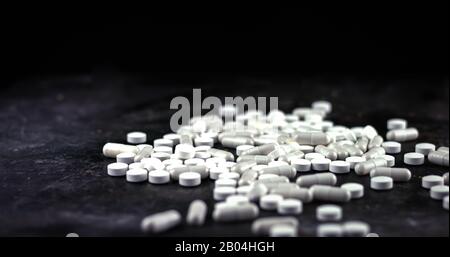 White medical pills and tablets laying on black background Stock Photo
