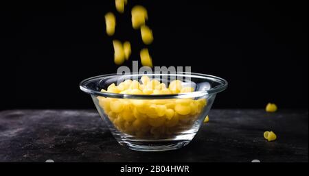 Raw Pasta falling in bowl isolated on black background. Stock Photo