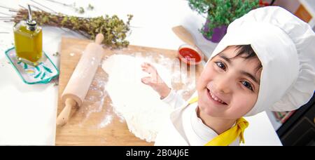 top view of a smiling child chef dressed in homely set Stock Photo