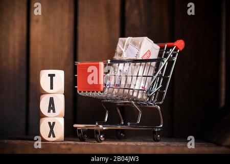shopping cart and cubes with the word "tax" on wooden background Stock Photo