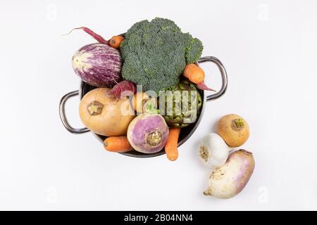 A lot of raw fresh vegetable in steel pot on white background, flat lay. Healthy cooking concept. Stock Photo
