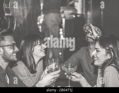 Happy friends cheering at cocktail jazz bar - Young trendy people having fun drinking alcohol and laughing - After dinner party concept - Focus on lef Stock Photo