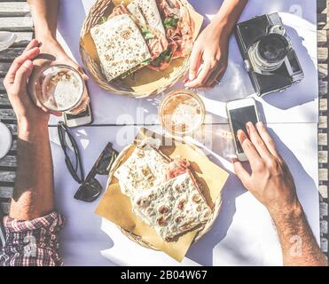 View from above of couple eating piadina sandwich and drinking beer in bar kiosk restaurant - Young people having fast meal sitting outdoor - Food and Stock Photo