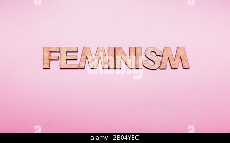 The word feminism in wooden letters on a pink background Stock Photo