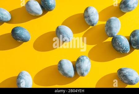 Blue textured colored Easter eggs on a bright yellow holiday background backdrop. Spring holiday concept. Copyspace. Flat lay. Top view Stock Photo