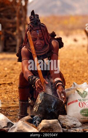 Himba woman cooking their traditional food made with wheat flour, Epupa Falls area, Kunene region, northern Namibia Stock Photo