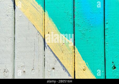 Wooden fence painted in white and turquoise with a yellow line. Close up. Texture, background Stock Photo
