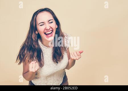 A girl in a T-shirt on a yellow background laughs out loud with pleasure. The concept of big discounts in stores. Toned. Close up. Stock Photo