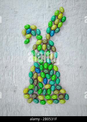 3D rendering of Easter bunny shape arranged from colorful easter eggs on wooden rustic surface shot from above Stock Photo