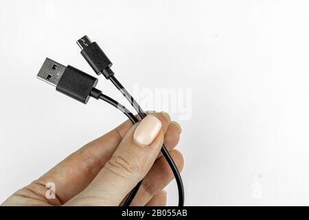 Hand holding usb to micro usb cable on white background copy space. Stock Photo