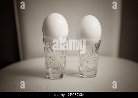 Two boiled chicken eggs in a crystal glasses on the table Stock Photo