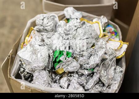 Recyclable waste collection, sorting and storage point center. Cardboard box bin full filled with crumpled used aluminium foil and other metal Stock Photo
