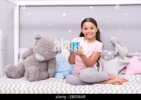 Hot milk before sleep. Health Benefits Drinking water before bed. Little child hold mug. Girl in pajamas drinking tea. Relaxation before sleep. Drinking milk just before bed. Bedtime beverage. Stock Photo