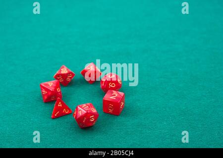 Close-up of a red polyhedral dice forming a circle on a green game table. In the image there is space for texts or graphics, copy space Stock Photo