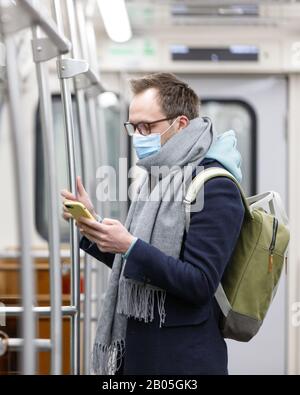 Ill man in glasses feeling sick, wearing protective mask against transmissible infectious diseases and as protection against the flu in transportation Stock Photo
