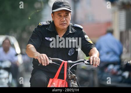 Chinese police officer riding a bicycle in Shanghai Old Town, Penglai Road, Huangpu,China Stock Photo