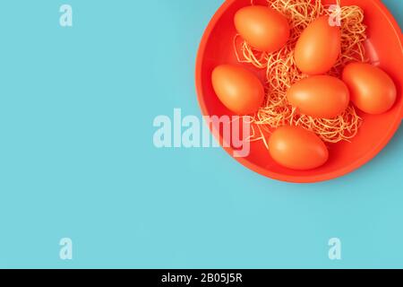 Close up of bright orange plate with Easter eggs on trendy blue-green backgrpound Stock Photo