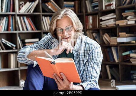 Interested young male student glasses enjoy interesting book library Stock Photo
