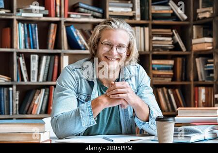 Portrait young student at home library desk smile look at camera Stock Photo